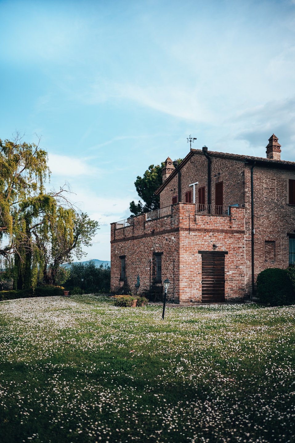 Una rustica villa in mattoni con tetto in cotto si trova in un prato erboso.