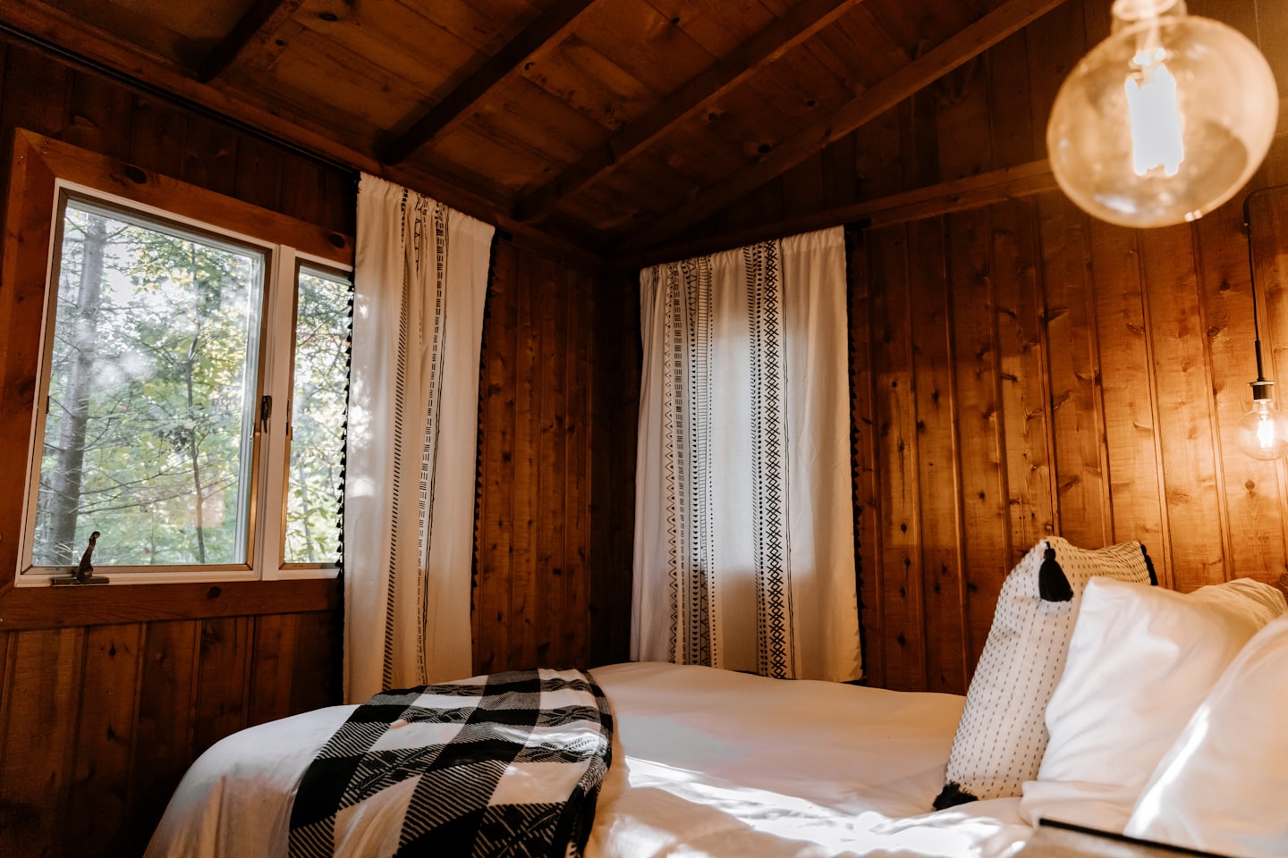 Camera da letto in legno con letto coperto da plaid.