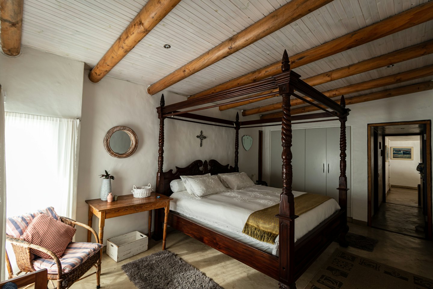 Camera da letto rustica con letto a baldacchino e travi in legno a vista.